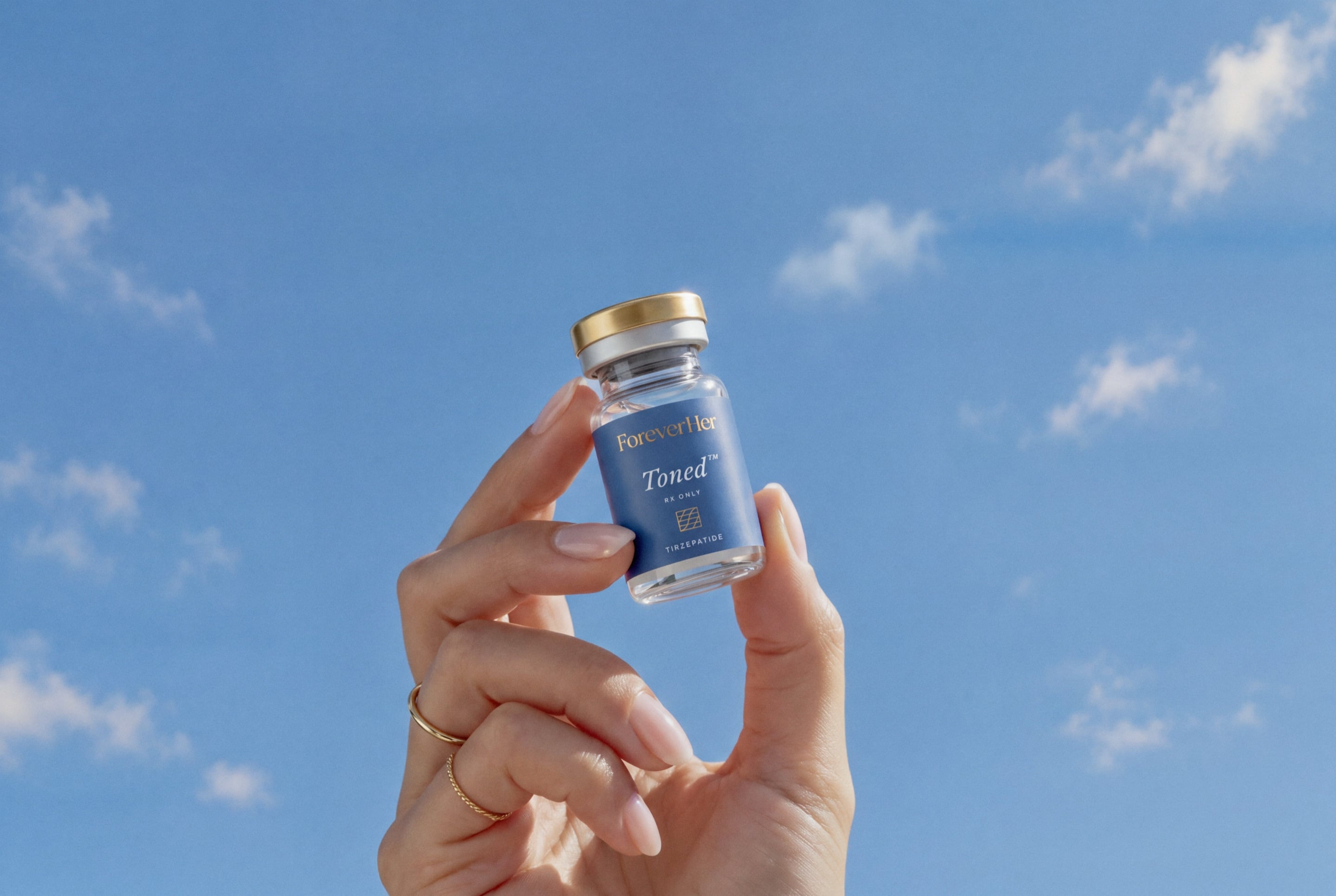 A hand holding a Toned vial against a blue sky